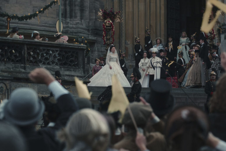 The bride and groom Sisi and Franz are standing in front of a cathedral, with cheering people a few stone steps below them.